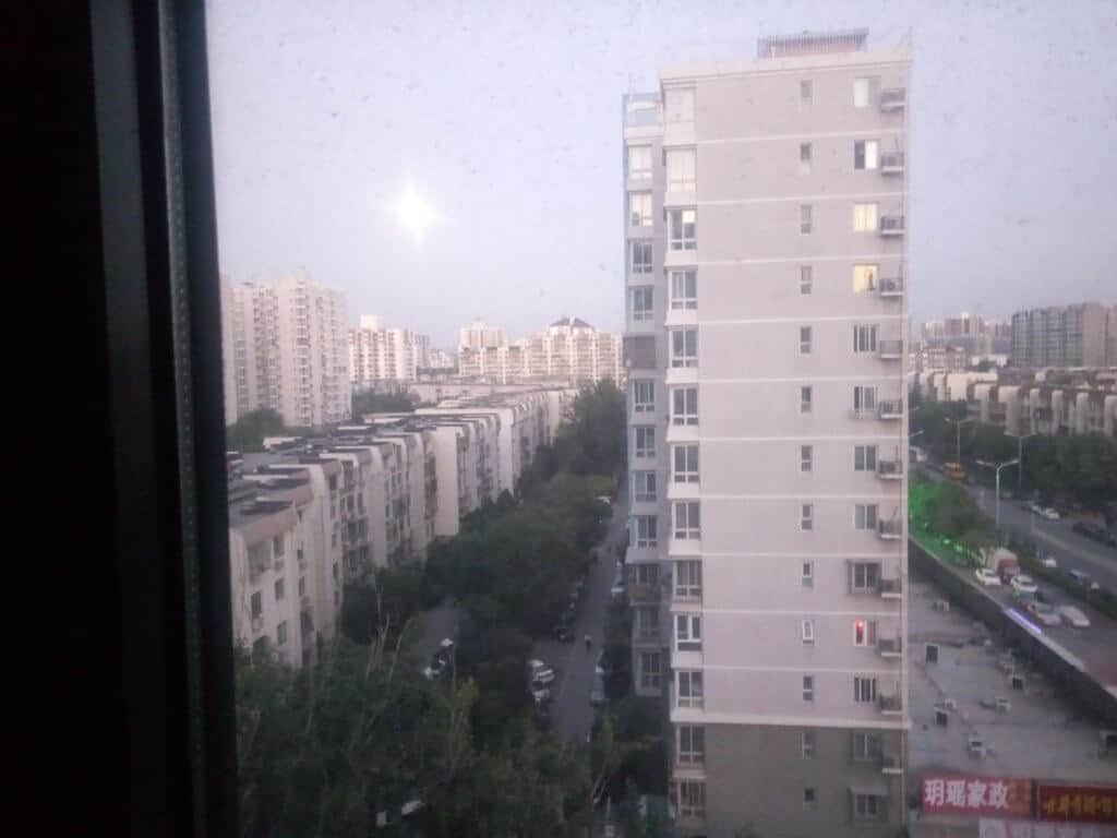 The view of some apartment buildings from my first apartment in China. Below you can see buildings, trees and people down below.