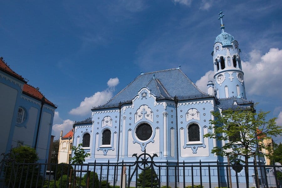 a Bright blue church building sitting behind a fence.