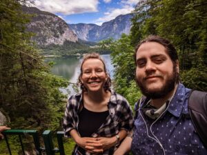 Lisa and Jenson Standing in front of a lake and mountain range in Halstatt, Austria
